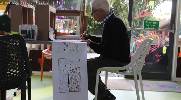 A man is creating an artwork on paper.