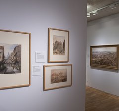 An installation photo of watercolour paintings hung on the wall in the Laing Art Gallery, showing several street scenes in the city.