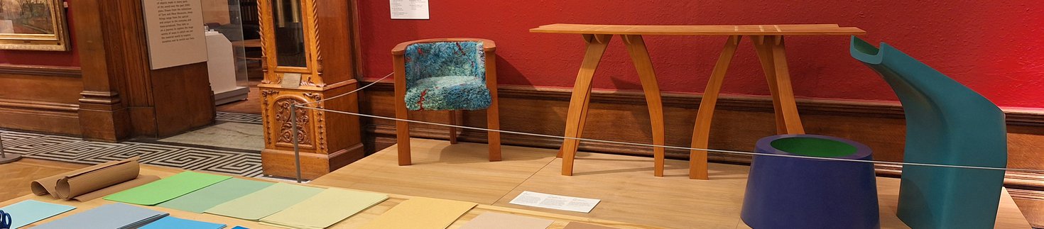 A photograph of the interior of the Shipley Art Gallery. There are paintings on the walls and craft supplies on a table.