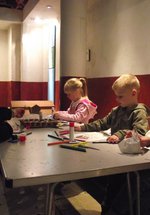 Two adults and two children sat at a table with pens and paper making crafts in the Roman Gallery