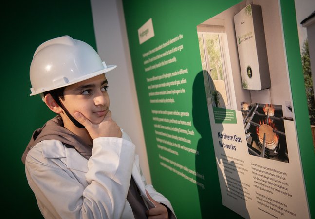 boy in hard hat looks panel thoughtfuly