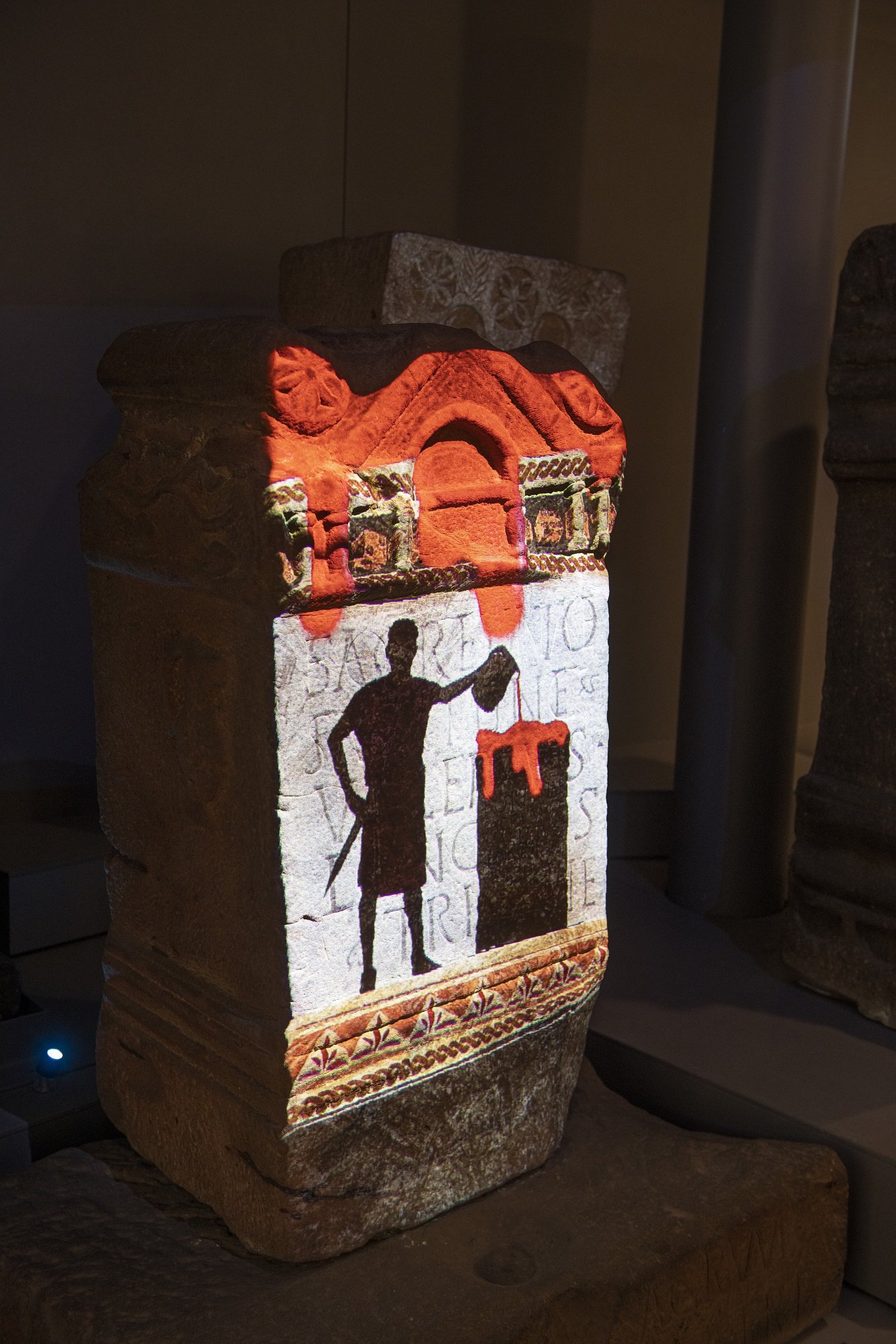 A Roman altar with an image projected onto it. It shows a soldier pouring either red wine or blood onto the top of an altar.
