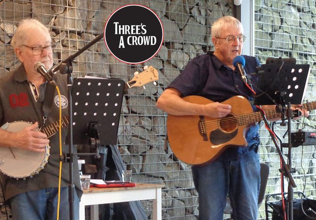 Two men playing guitar and banjo on a stage 