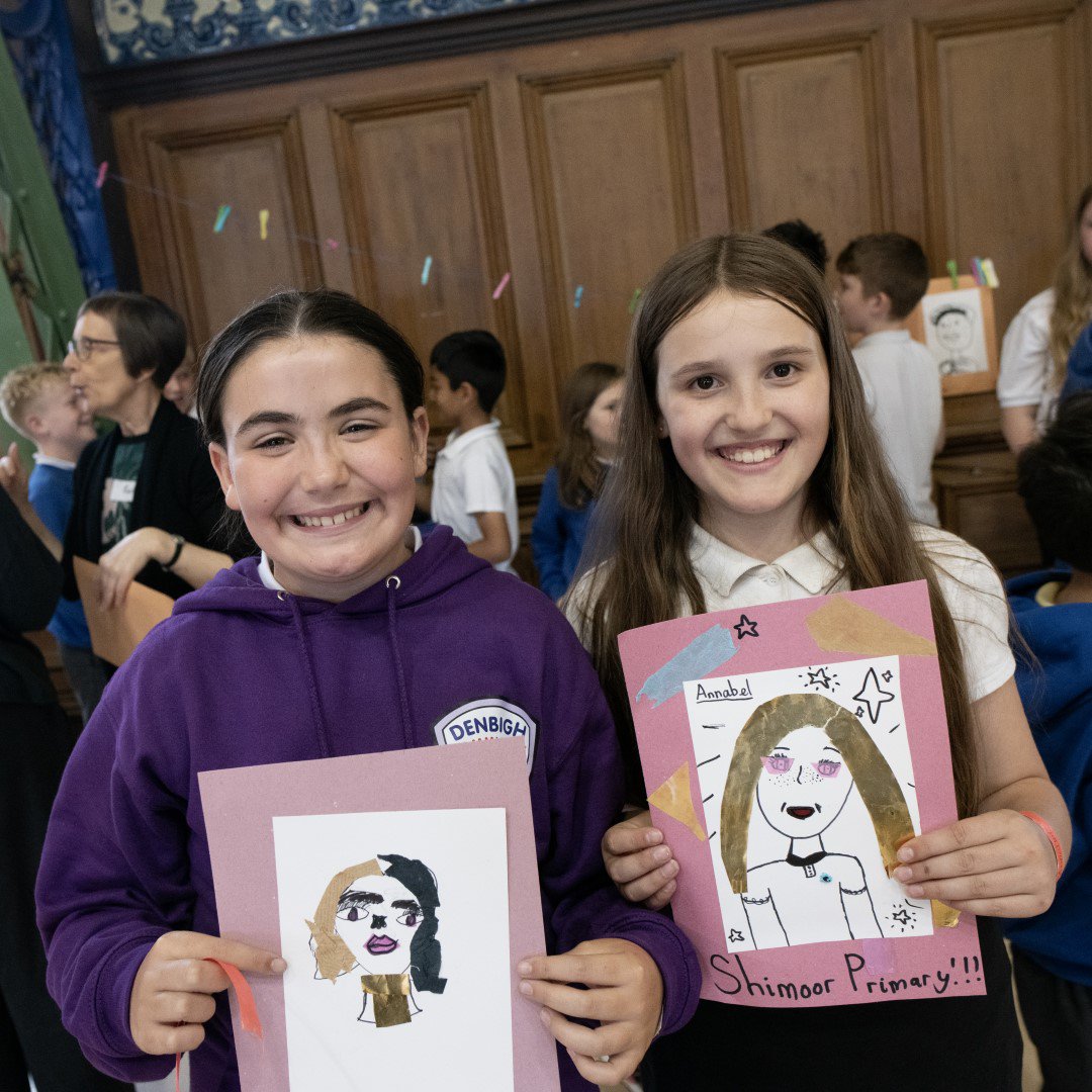 Two schoolchildren showing their artworks