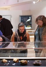 Three people are looking into a musuem case full of objects