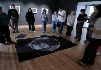 A group of young people standing around an artwork of the moon