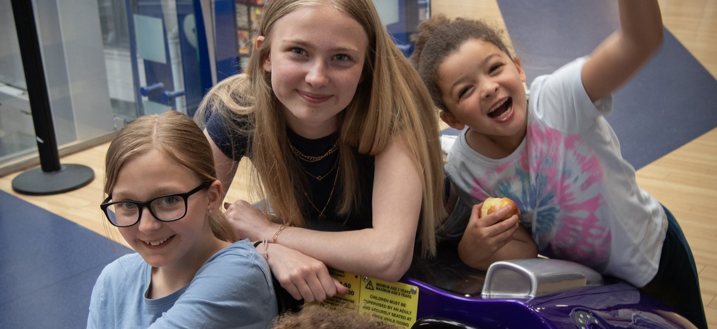 Three girls of various age sitting having fun in the museum 