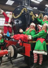 Group of elves laughing in front of locomotive