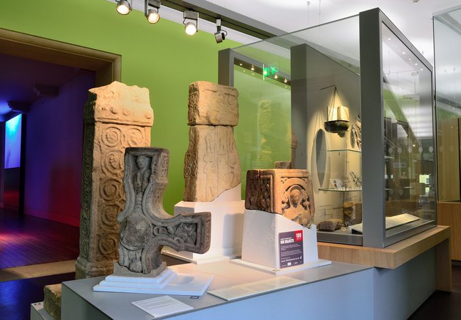 Four Anglo-Saxon carved stone artefacts. One is a fragment of a cross