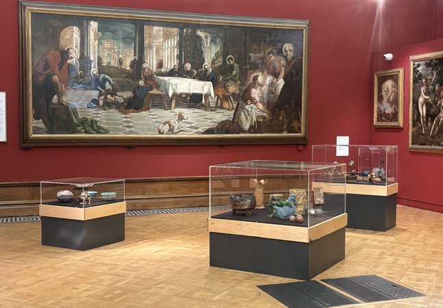 Three glass display cases with ceramic objects in a art gallery.