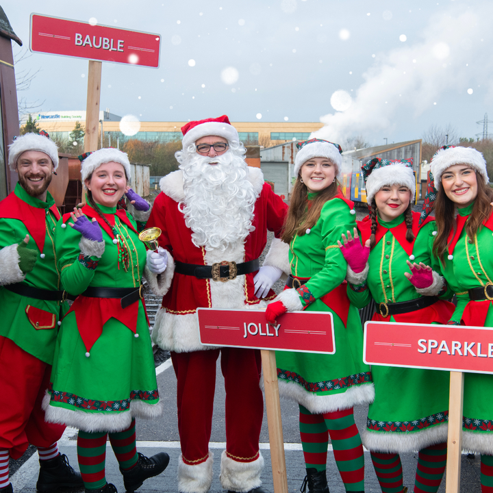 Elves and Santa smiling at the platform at Stephenson Steam Railway