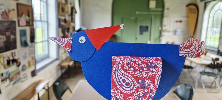 A piegoen made out of paper wearing a santa hat