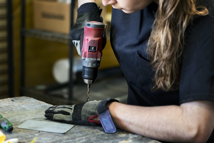 A woman operating a drill.