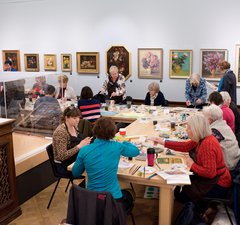 art class group sitting down at table painting in an art gallery