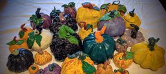 A colourful array of painted ceramic pumpkins on a white table cloth.