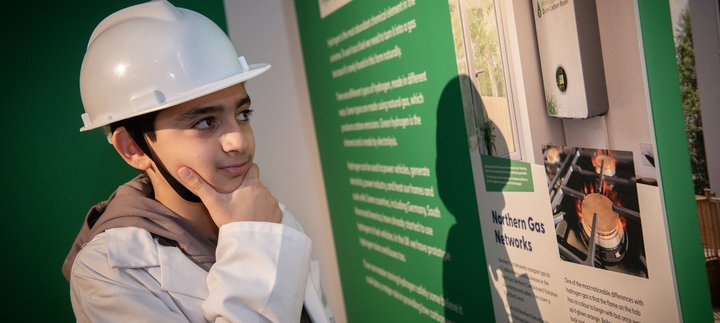 boy in hard hat looks panel thoughtfuly