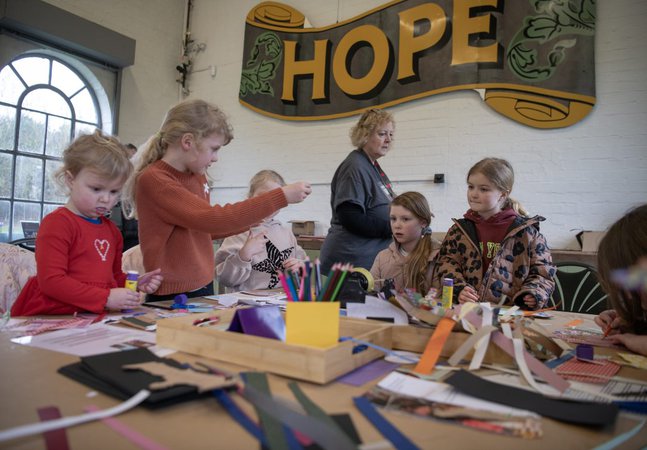 A group of children sit round a crafting table 
