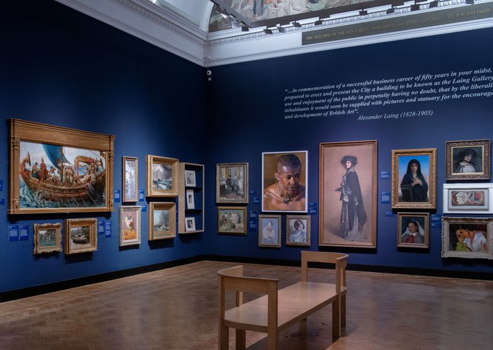 A photograph of the inside of an art gallery with oil paintings in gold frames.