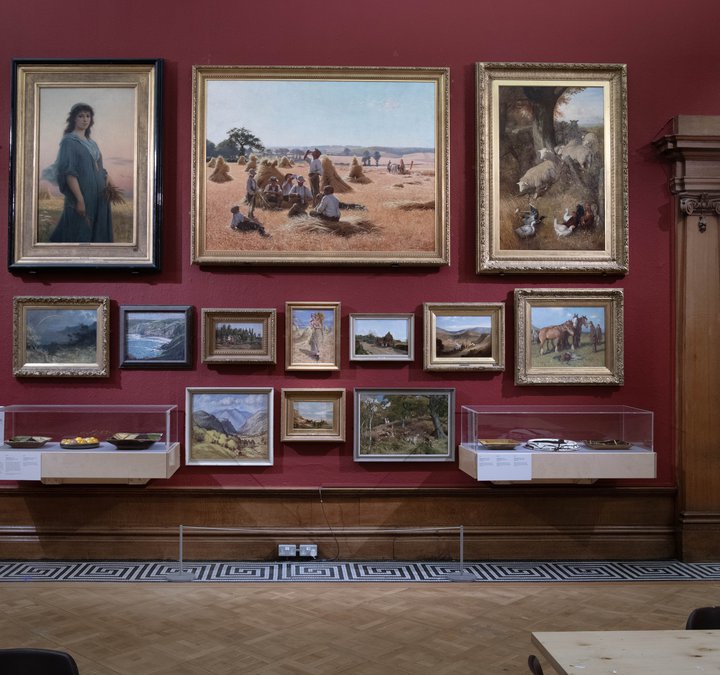 A red gallery wall with historic paintings in gold frames