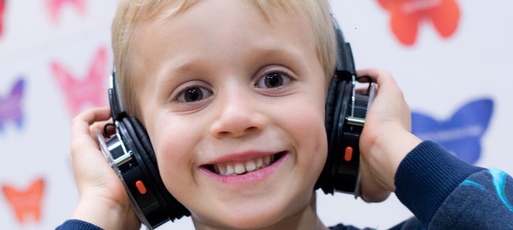 Boy smiles at camera wearing headphones