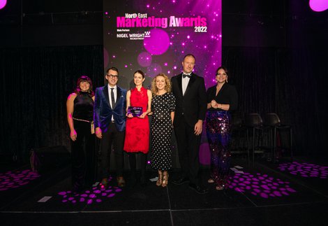 A group of people on a purple lit stage collecting an award