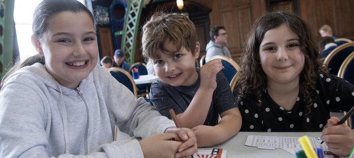 two girls and a boy smile while doing crafts