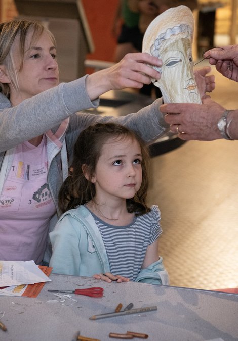 Woman helping to put mask on young girl
