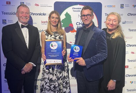 Four people accepting an award at a ceremony.