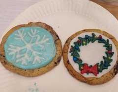 A photograph of two decorated cookies featuring a snowflake and a Christmas wreath