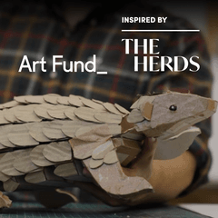 A photo of a cardboard Pangolin puppet. The image includes an ‘Art Fund’ logo and an ‘Inspired by the herds’ logo.