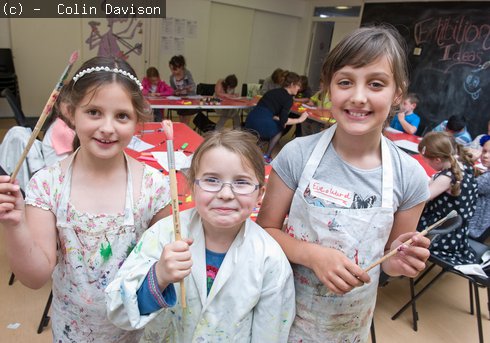 three girls holding paintbrushes