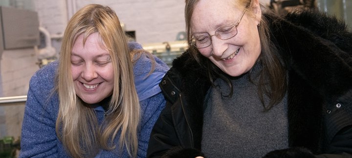 two women smile and talk in the museum