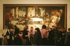 Group of people chatting to each other in front of a huge oil painting in an art gallery