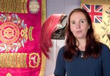 Woman stand s in front of regimental flag talking 