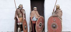 three Roman soldiers stand in front of the reconstructed Barrack Block