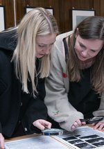 two women bending over to get a closer look at an archival ledger