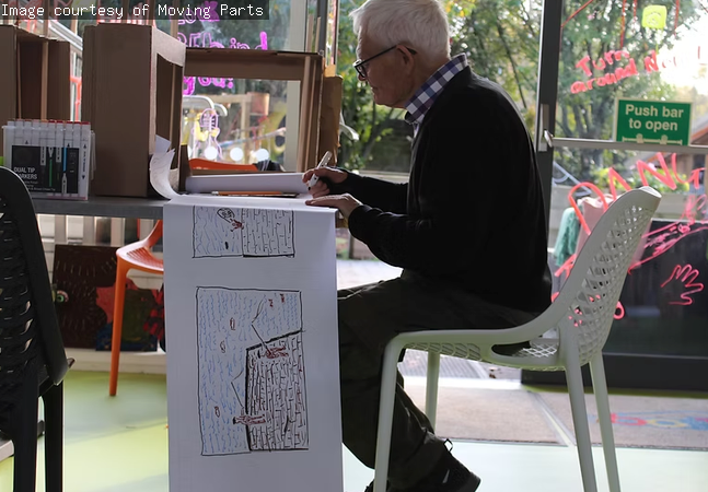 A man is creating an artwork on paper.