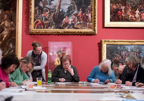group of people making art in front of beautiful paintings