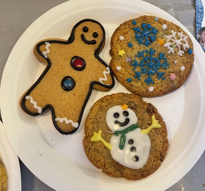 A photograph of three cookies: one gingerbread man, one with a snowman decoration, and one with snowflakes.
