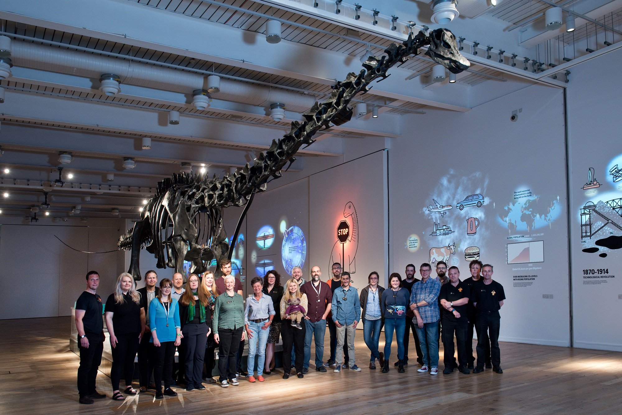 Staff at the Great North Museum stand underneath a replica skeleton of a Diplodocus