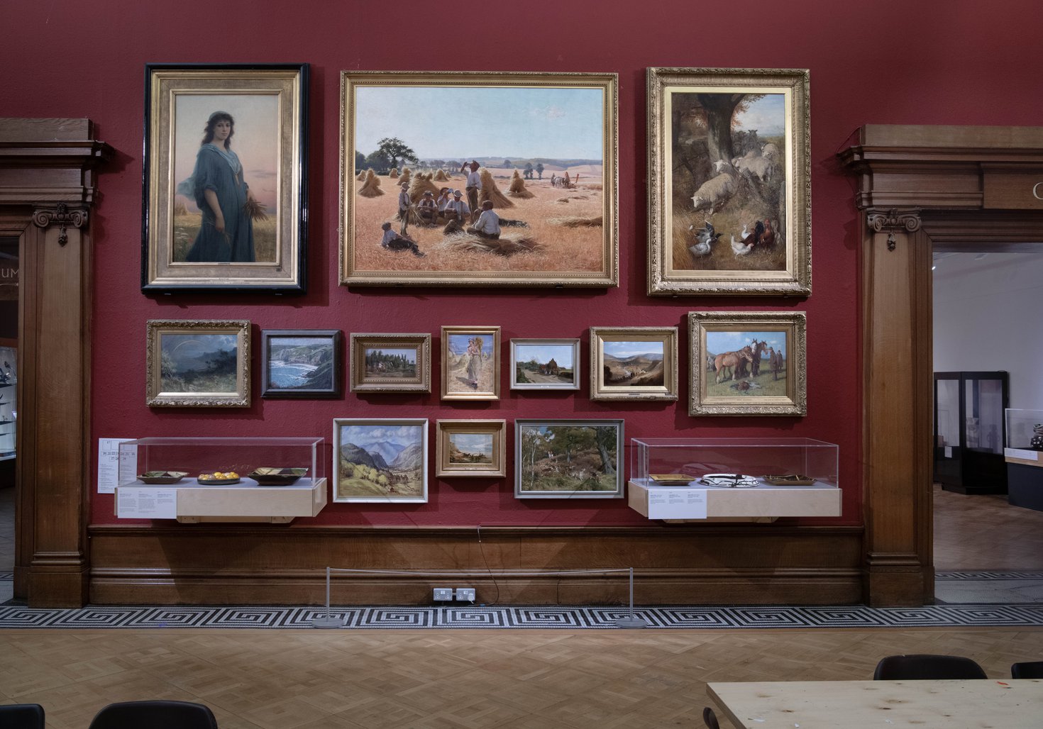 A red gallery wall with historic paintings in gold frames