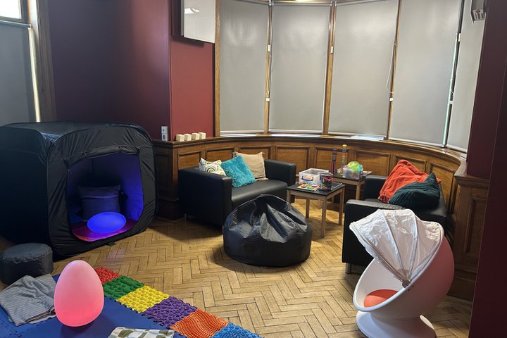 A room with soft furnishings and sensory toys and mats out on a wooden floor