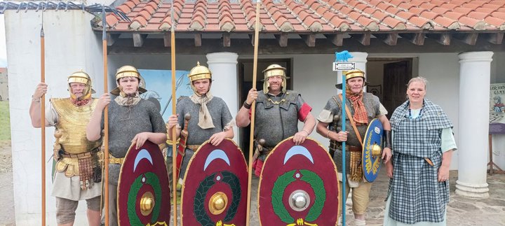 The Tungrian re-enactment group in replica Roman costumes outside the reconstructed buildings