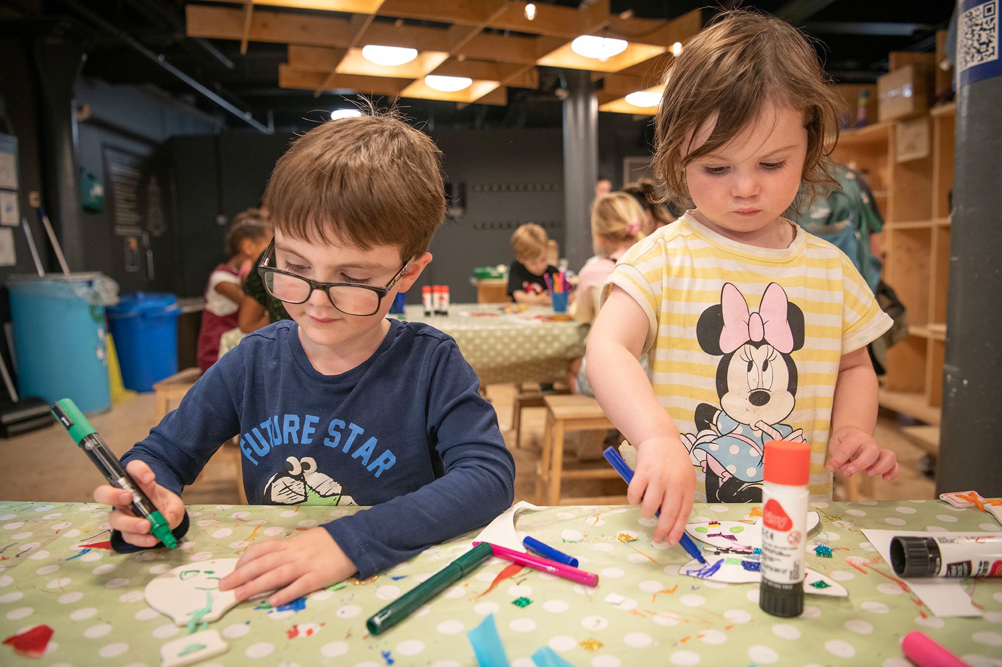 Two young children crafting in a museum.