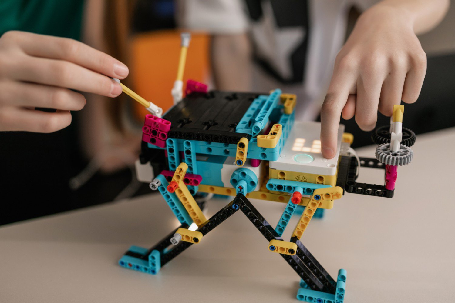 Child's hands building a LEGO robot.