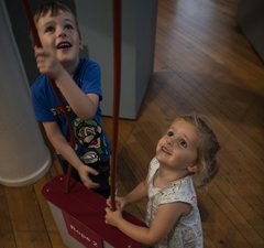 Two small children in gallery playing on pulley 