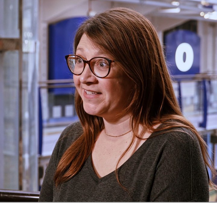 Screenshot of talking women with brown hair in museum