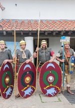 The Tungrian re-enactment group in replica Roman costumes outside the reconstructed buildings