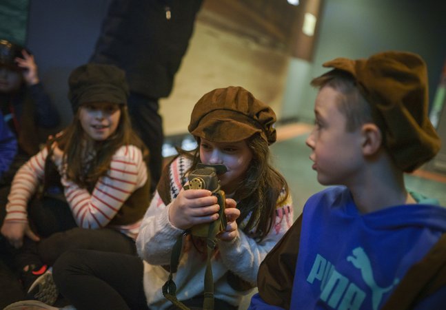 Children sat looking through a looking glass as part of a workshop at Woodhorn Museum.