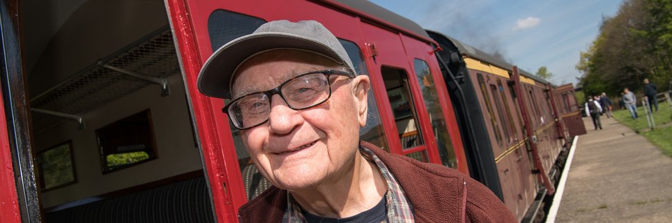 Man wearing cap standing next to railway carriage